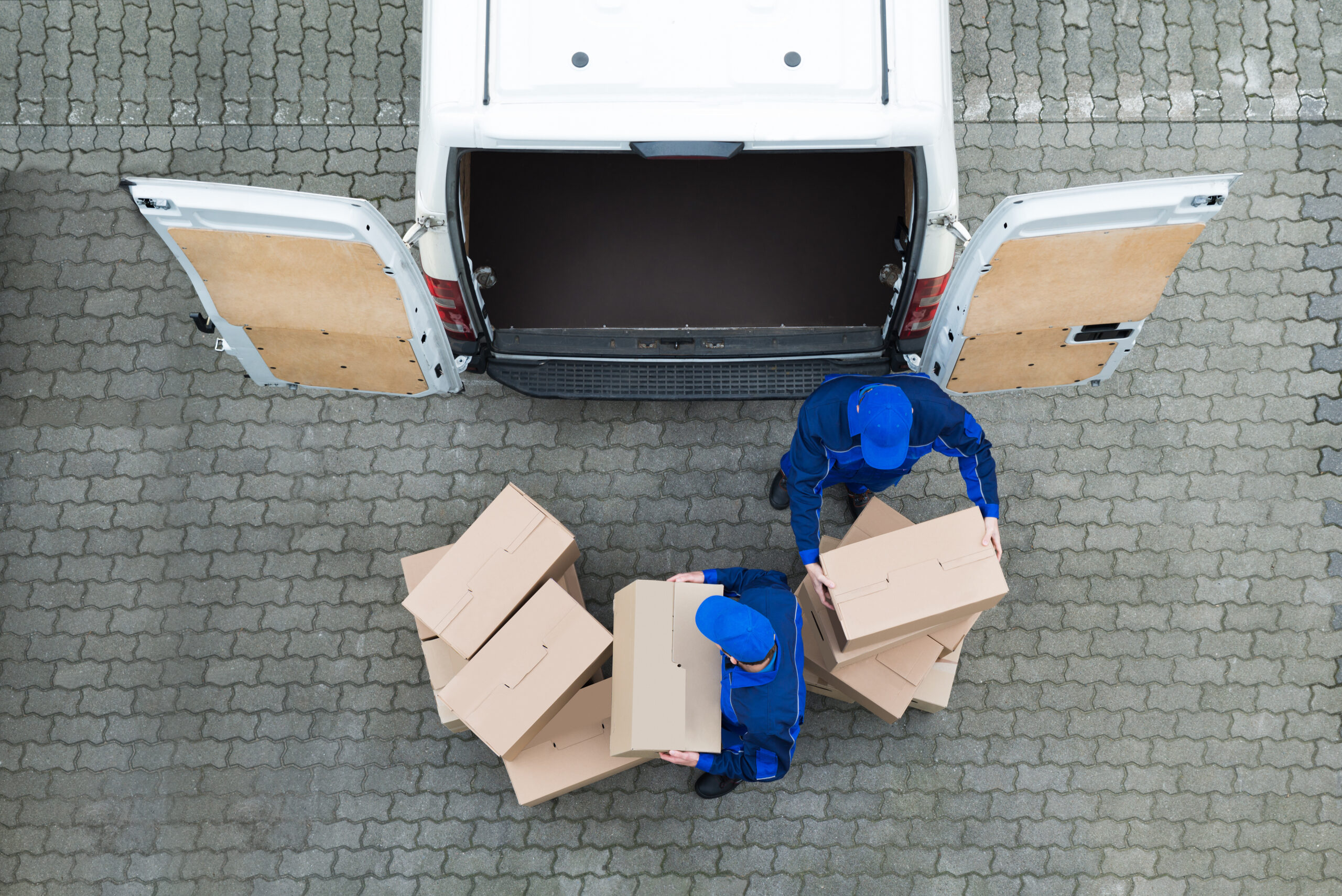 Overhead view of delivery workers handling parcels beside a van